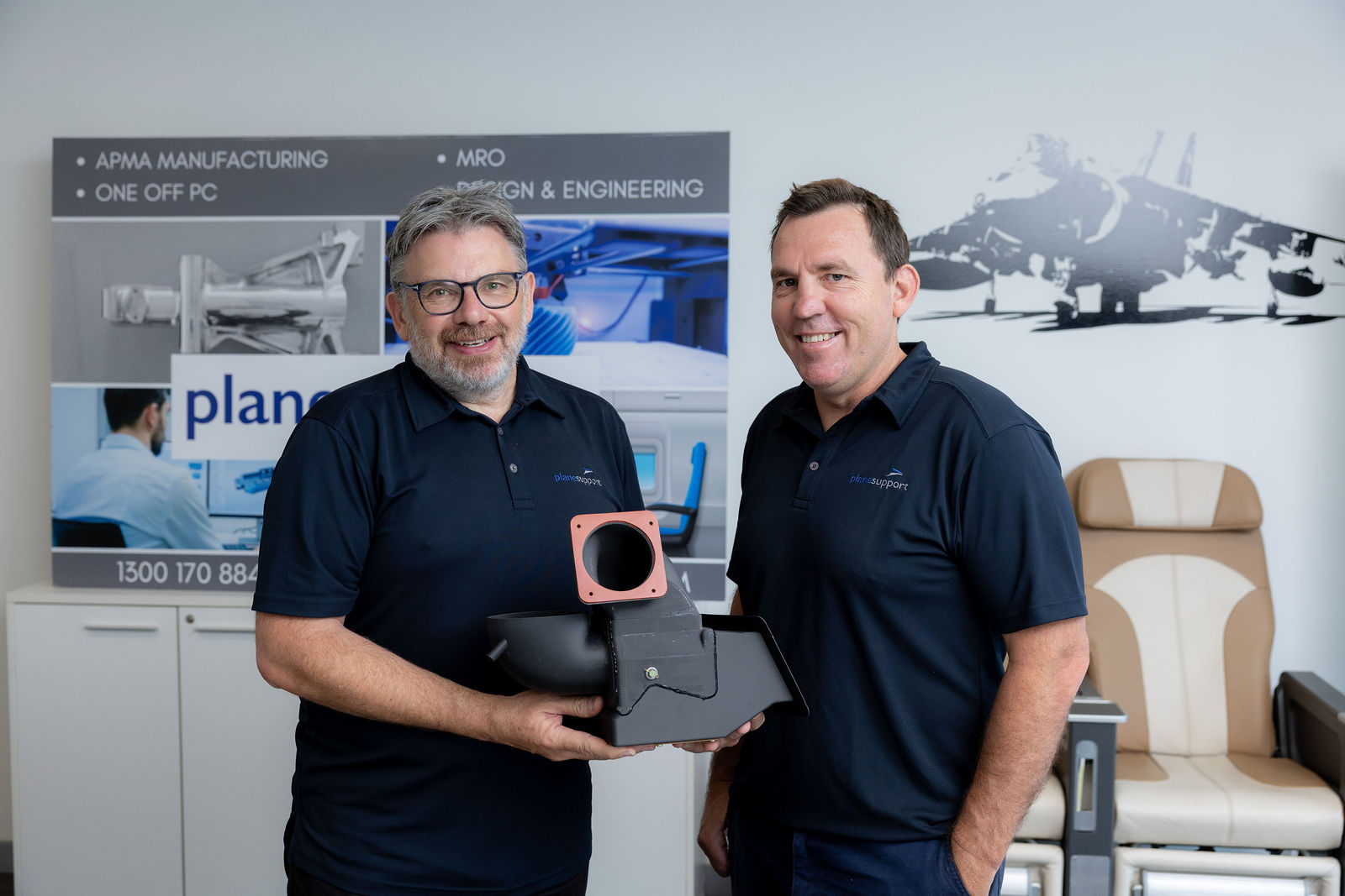 Plane Support team members holding a 214B helicopter ducting component made using additive manufacturing